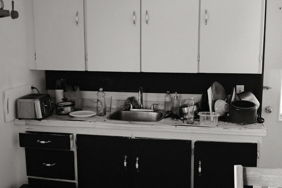 A cluttered kitchen counter with a sink, toaster, and various dishes
